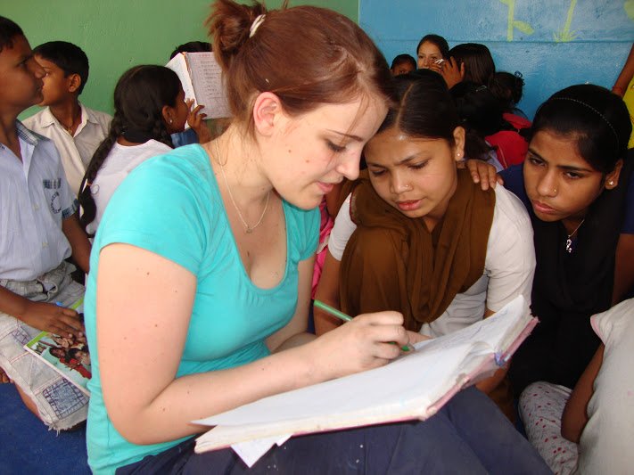 A volunteer helping teenage girls with their written work