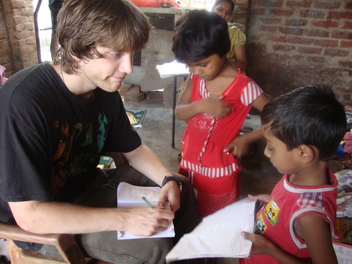 A volunteer helping two young children with their writing