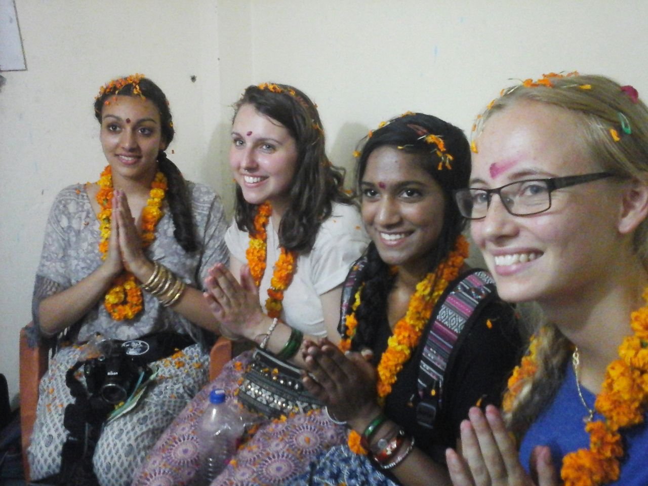 Four new volunteers in marigold garlands, palms together in a namaste