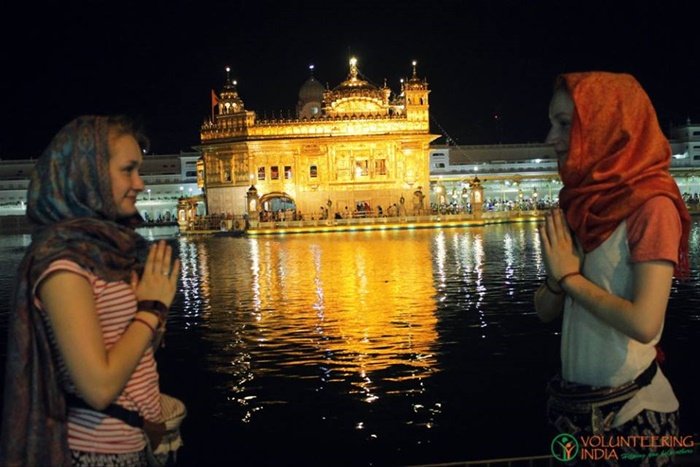 Two volunteers with covered heads at the Golden Temple in Amritsar at night