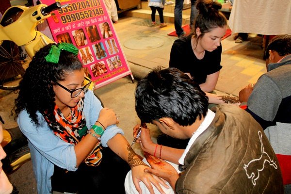 Volunteers having their hands decorated with henna at a market