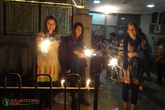 Three volunteers in kurtas holding sparklers at Diwali