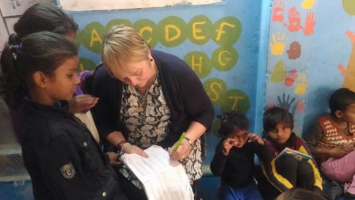 An older volunteer going through a worksheet with a girl at a children’s center