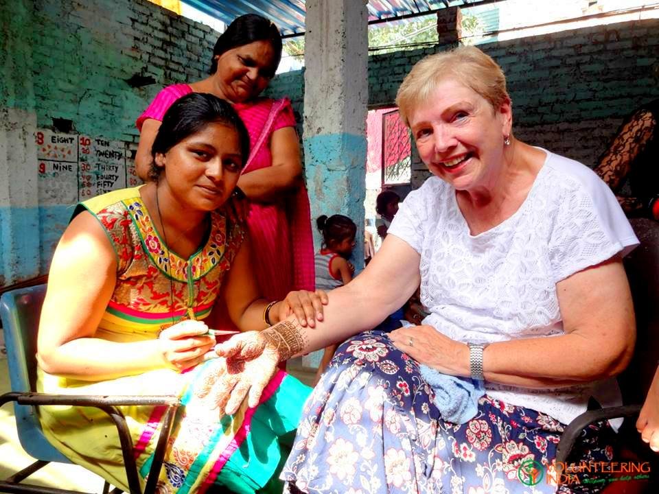 A woman applying henna to an older volunteer’s hand