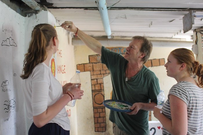Teacher Robert and two students painting a school wall