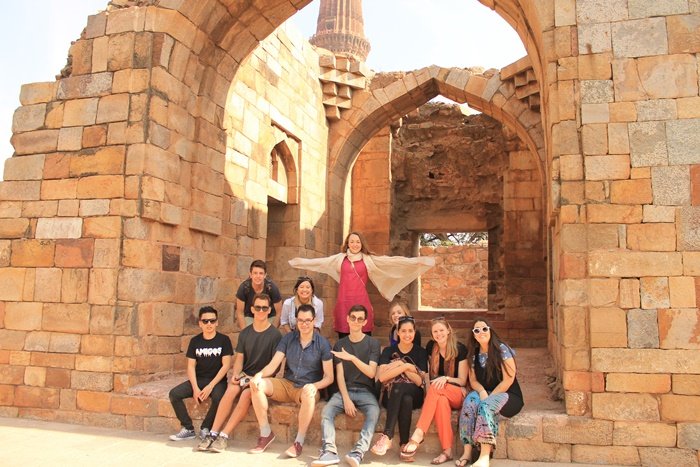 A group of volunteers sitting among the ruins of the Qutub Minar complex in Delhi