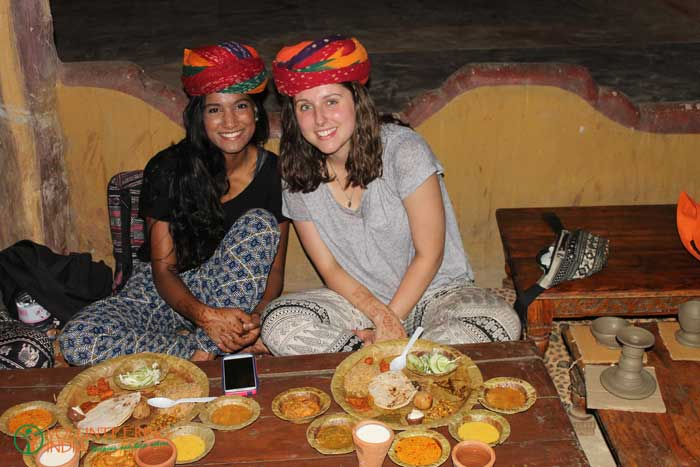 Two volunteers in Rajasthani turbans sharing a thali dinner