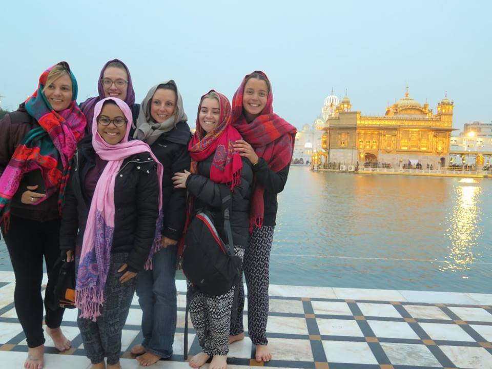 Six volunteers in headscarves beside the pool at the Golden Temple in Amritsar