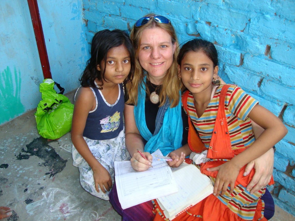 A volunteer helping two girls with their schoolwork
