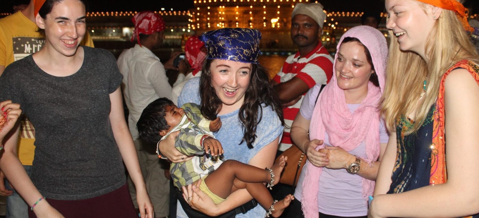 Volunteers in orange headscarves at the Golden Temple in Amritsar at night