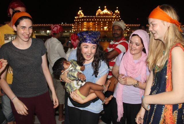 Volunteers in orange headscarves at the Golden Temple in Amritsar at night