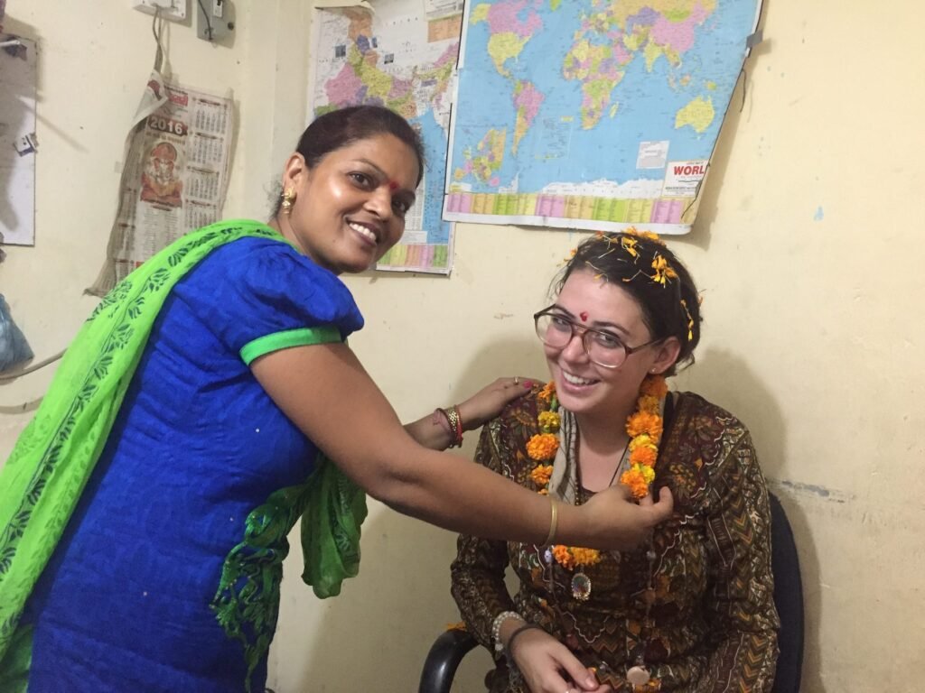 A teacher placing a marigold garland on a new volunteer in Delhi