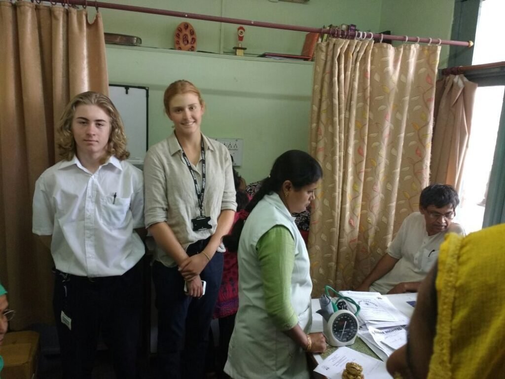 Pre-medical volunteers in white coats with a doctor at a clinic in Delhi