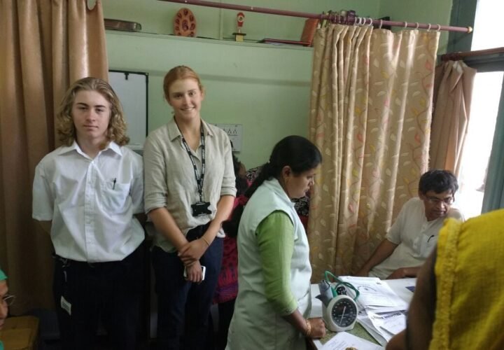 Pre-medical volunteers in white coats with a doctor at a clinic in Delhi