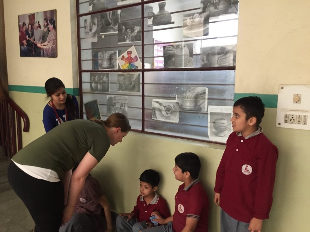 A volunteer and a teacher with students in a corridor at a special needs center in Delhi