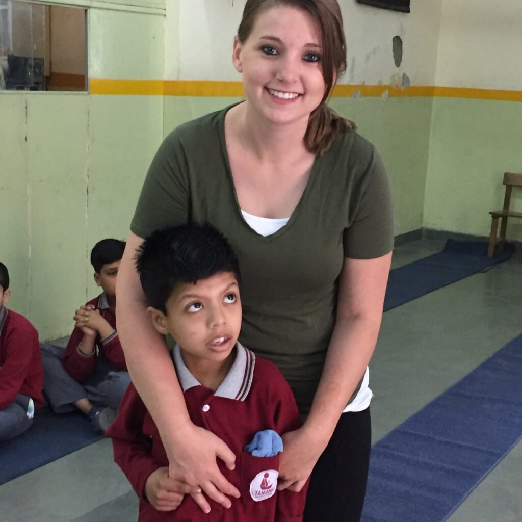 A smiling volunteer with a young student at a special needs center in Delhi