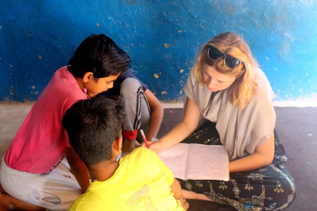 A volunteer helping two boys with their writing at a project in Delhi