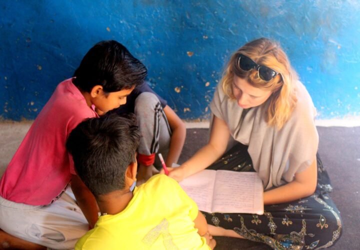 A volunteer helping two boys with their writing at a project in Delhi