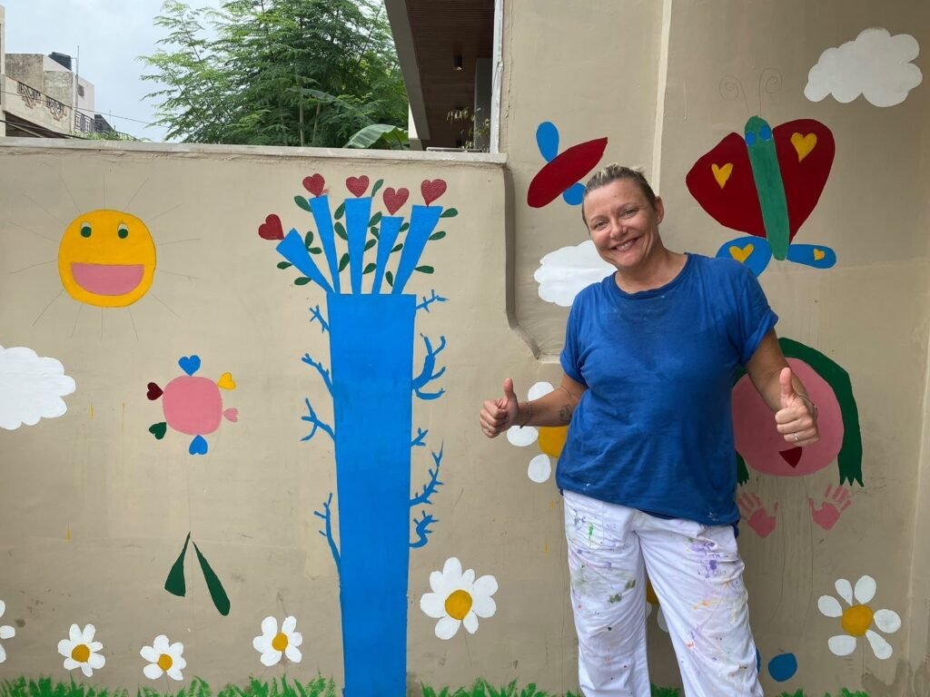 A volunteer painting a flower mural on a wall in Jaipur
