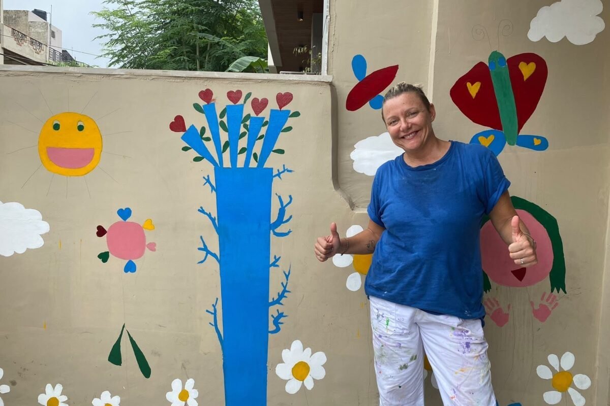 A volunteer painting a flower mural on a wall in Jaipur