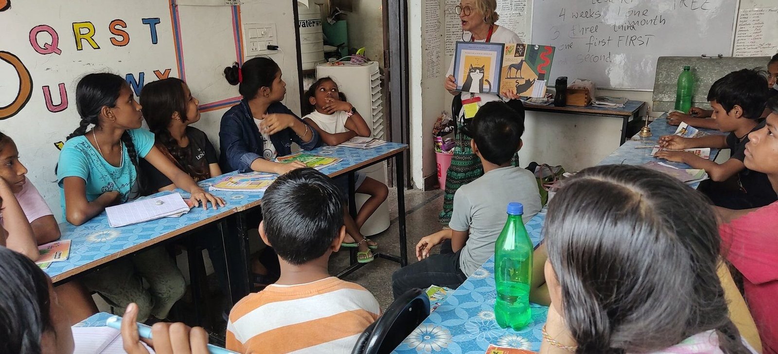 A volunteer teaching a class of children at their desks in Jaipur