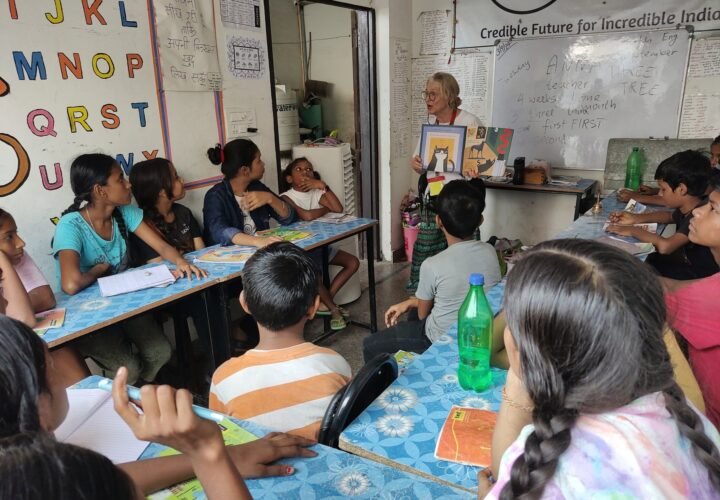 A volunteer teaching a class of children at their desks in Jaipur