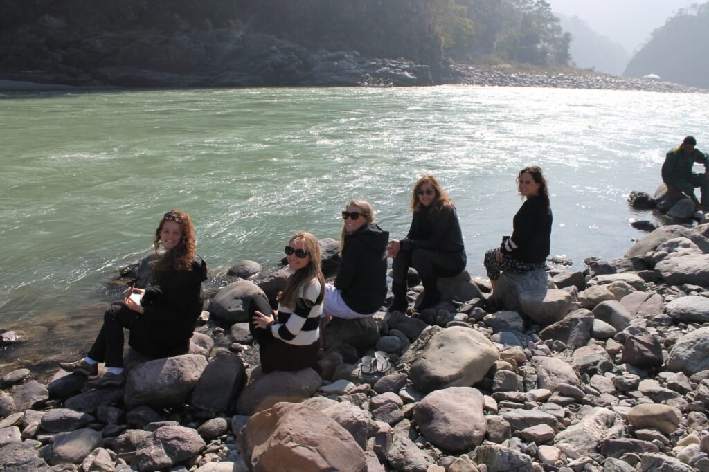 Volunteers sitting on the rocks beside the Ganges at Rishikesh