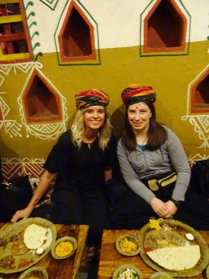 Two volunteers in Rajasthani turbans with their thalis at a village-style restaurant